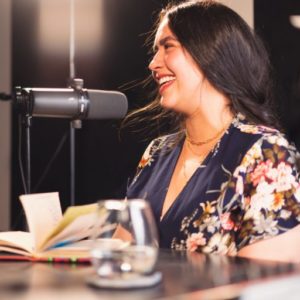 A young woman smiles as she records a book in a studio