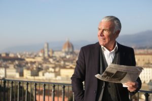 A gentleman reads the newspaper with a view of the city in the background